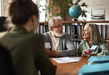 Close up of senior couple in travel agency making reservation for holiday. Eldery couple traveling in retirement. - HPIF34087