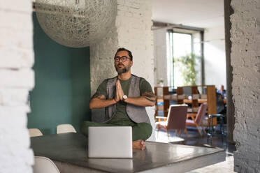 Young man sitting and meditating in the office. - HPIF34125