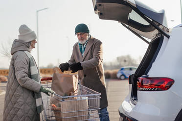 Senior couple going home from a grocery store, having fun. - HPIF34137