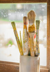Set of paint brushes on jar, in front of a window - ADSF50070