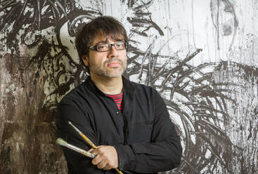 Painter artist with black glasses posing in front of his mural paint - ADSF50071