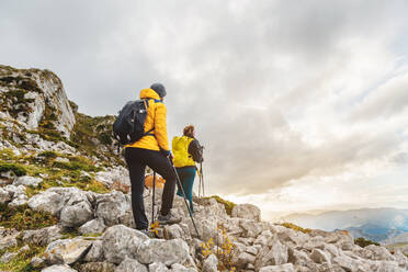 Two mountaineers on a hiking trail equipped with a backpack, warm clothes and trekking poles. couple hiking in high mountains - ADSF50205