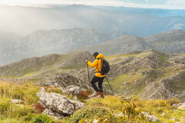 Wanderer, der mit Rucksack, Trekkingstöcken und warmer Kleidung eine Bergstrecke zurücklegt. Hochgebirgssport. Berglandschaft. - ADSF50206