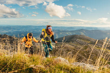 Zwei Wanderer mit Rucksäcken, Trekkingstöcken und warmer Kleidung auf einer Bergstrecke. Sport und Outdoor-Aktivitäten - ADSF50210