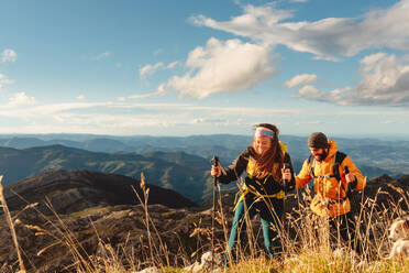 Ein paar Wanderer mit Rucksäcken, Trekkingstöcken und warmer Kleidung auf einer Bergtour. Outdoor-Sport und Abenteuer. - ADSF50214