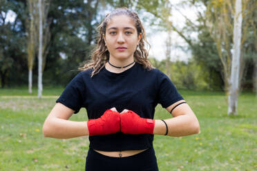 Weiblicher Boxer Porträt mit Händen roten Verband wickeln für Boxtraining. Kampfsport im Freien. - ADSF50234