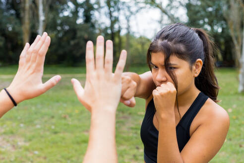 Junge multiethnische Boxerin beim Training im Freien, Sparring und Schlagtraining in einem Stadtpark. - ADSF50236