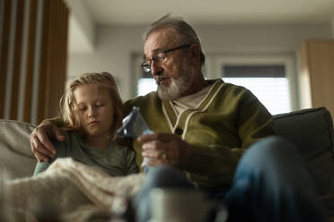 Ein älterer Mann kümmert sich um seine kranke Enkelin. - HPIF34184