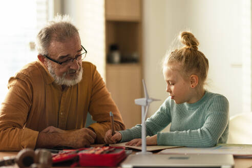 Ein älterer Mann lernt mit seiner Enkelin. - HPIF34195
