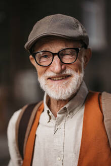 Studio portrait of a senior man with glasses and a beret on his head. Handsome smiling elderly man. - HPIF34256