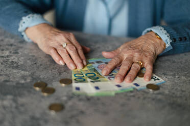 Nahaufnahme einer älteren Frau, die ihre Rente zu Hause zählt. - HPIF34269