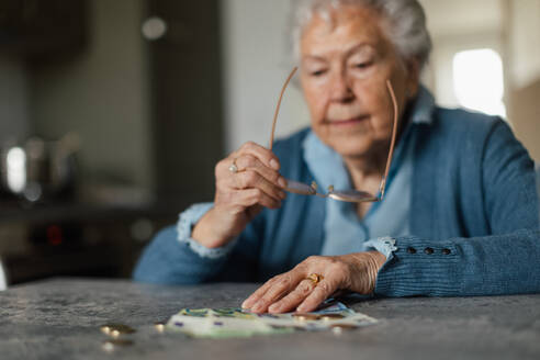Unglückliche Seniorin, die zu Hause ihre Rente zählt. Finanzielle Probleme älterer Menschen. - HPIF34270