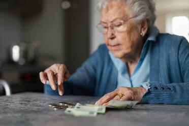 Eine unglückliche Seniorin, die zu Hause ihre Rente zählt. - HPIF34271