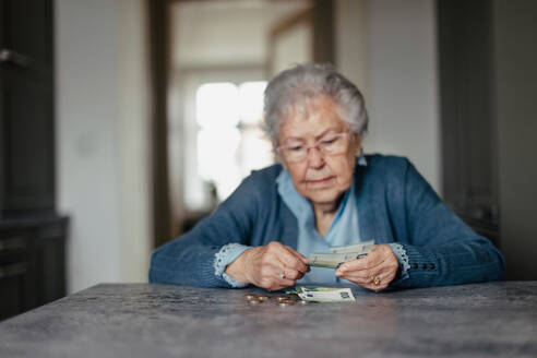 Eine unglückliche Seniorin, die zu Hause ihre Rente zählt. - HPIF34272