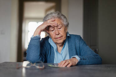 Eine unglückliche Seniorin, die zu Hause ihre Rente zählt. - HPIF34273