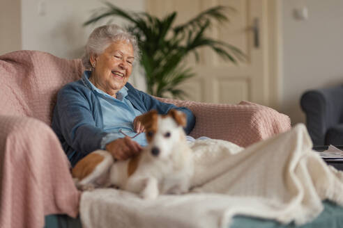 Senior woman enjoying time with her little dog at home. Dog as companion, best friends for senior. - HPIF34275