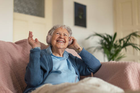 Porträt einer älteren Frau, die zu Hause sitzt und telefoniert. Ältere Frau, die mit ihrem Smartphone spricht. - HPIF34280