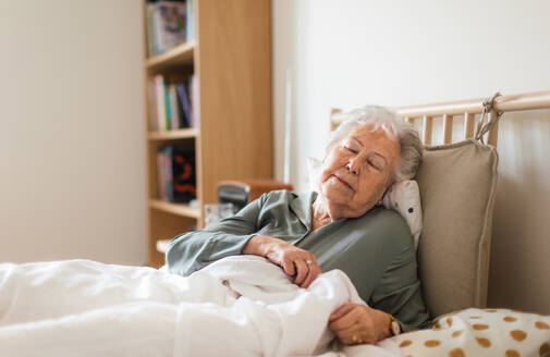 Senior woman sleeping in her bed alone. Woman having pain a feeling anxious. Loneliness and social isolation of eldery woman. - HPIF34285