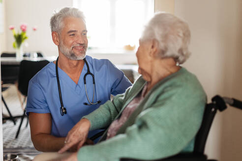 Pflegerin bei der regelmäßigen Untersuchung einer älteren Klientin in ihrem Haus. Fürsorglicher Pfleger, der sich um eine ältere Patientin im Rollstuhl kümmert. - HPIF34294