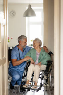 Caregiver doing regular check-up of senior client in her home. Thoughful male nurse taking care of eldery patient on wheelchair. - HPIF34298