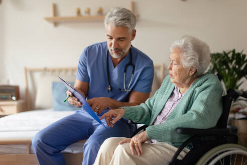 Caregiver doing regular check-up of senior client in her home. - HPIF34304