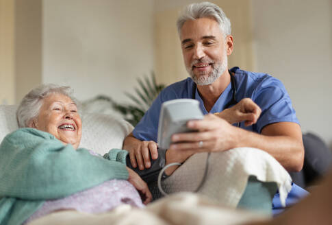 Caregiver doing regular check-up of senior client in her home. - HPIF34308