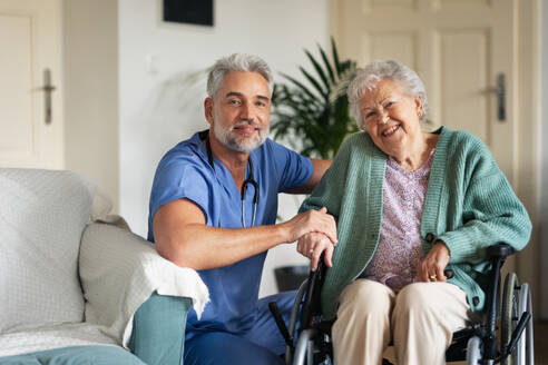 Pflegerin bei der regelmäßigen Untersuchung einer älteren Klientin in ihrem Haus. Fürsorglicher Pfleger, der sich um eine ältere Patientin im Rollstuhl kümmert. - HPIF34314