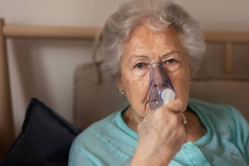 Porträt einer älteren Frau mit Inhalator, Konzept für das Gesundheitswesen. Nahaufnahme einer älteren Patientin mit Sauerstoffmaske. - HPIF34327
