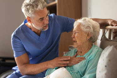 Doctor helping senior patient with chest pain. Thoughful male nurse taking care of eldery patient struggling with breathing. - HPIF34332