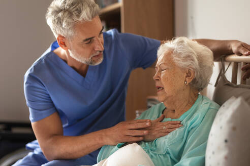 Ein Arzt hilft einem älteren Patienten mit Brustschmerzen, ein Pfleger kümmert sich um einen älteren Patienten, der mit dem Atmen kämpft. - HPIF34332