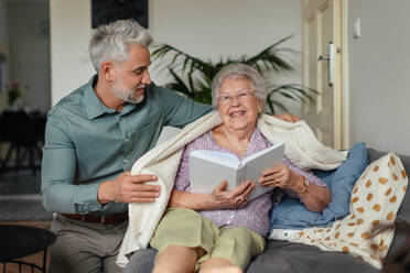 Ältere Frau, die eine schöne Zeit mit ihrem erwachsenen Sohn verbringt, der ein Buch liest, Konzept von Beziehungen. - HPIF34344