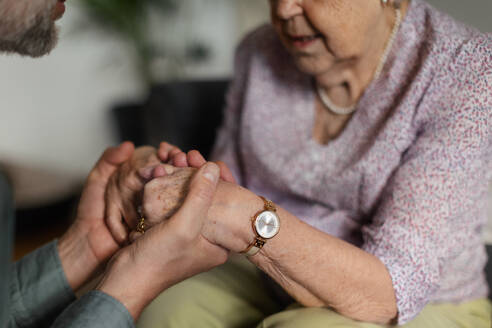 Close up of son holding hands of his senior mothe, concept of healthcare and relationships. - HPIF34348