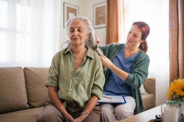 Krankenschwester verbringt viel Zeit mit einer älteren Frau zu Hause und kämmt ihr schönes Haar. - HPIF34358