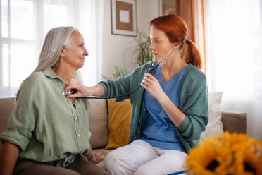 Krankenschwester untersucht älteren Patienten mit Stethoskop zu Hause. - HPIF34362