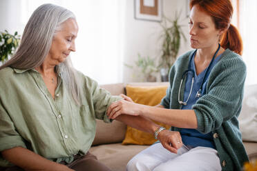 Krankenschwester berät eine ältere Frau zu Hause über ihren Gesundheitszustand. - HPIF34366
