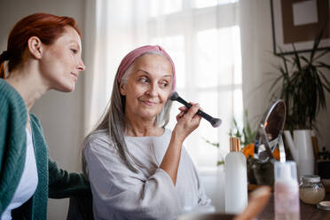 Eine ältere Frau schminkt sich zu Hause. - HPIF34414