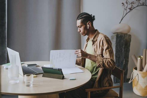 Young man reading book and studying at home - YTF01492