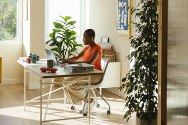 Businesswoman working remotely at desk in modern home office - EBSF04223