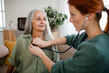 Nahaufnahme einer Krankenschwester, die einen älteren Patienten zu Hause mit einem Stethoskop untersucht. Eine Ärztin hört die Atmung und das Herz eines älteren Patienten ab. Untersuchung nach einer Herzoperation. - HPIF34420