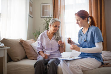 Krankenschwester erklärt einer älteren Frau die Einnahme von Medikamenten. Weibliche Pflegekraft kümmert sich um einen älteren Patienten. - HPIF34432
