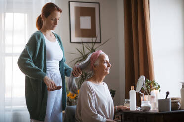 Krankenschwester verbringt Zeit mit einer älteren Frau zu Hause und kämmt ihr schönes Haar. Reife Frau kümmert sich um ihre ältere Mutter. - HPIF34443