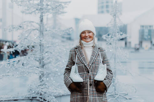 Porträt einer glücklichen älteren Frau im Winter auf einer Eislaufbahn im Freien. - HPIF34446