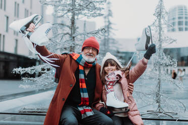 Porträt von Großvater und Enkelin im Winter auf einer Eislaufbahn im Freien. - HPIF34451