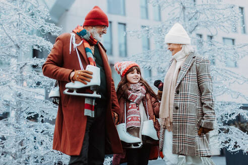 Senioren mit ihrer Enkelin im Winter auf einer Eislaufbahn im Freien. - HPIF34453