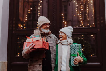 Happy senior couple enjoying outdoor christmas market, buying gifts. - HPIF34459