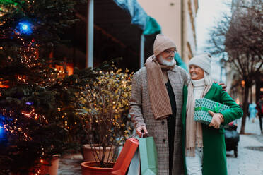 Glückliches älteres Paar genießt den Weihnachtsmarkt im Freien und kauft Geschenke. - HPIF34462