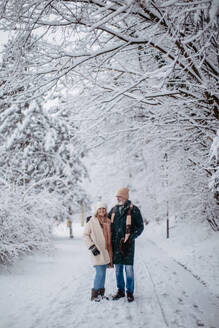 Elegantes älteres Paar, das im verschneiten Park spazieren geht, während eines kalten, verschneiten Wintertages. Älteres Paar, das Winterurlaub in den Bergen verbringt. Winterliche Landschaft. - HPIF34468