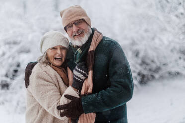 Waist up Porträt der eleganten Senior Paar zu Fuß in den verschneiten Park, während der kalten Winter verschneiten Tag. Älteres Paar verbringen Winterurlaub in den Bergen. Wintry Landschaft. - HPIF34472