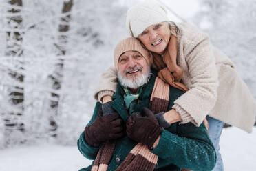 Nahaufnahme eines eleganten älteren Mannes mit seiner Frau im verschneiten Park an einem kalten Wintertag. Älteres Ehepaar im Winterurlaub in den Bergen. Winterliche Landschaft. - HPIF34496