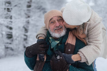 Nahaufnahme eines eleganten älteren Mannes mit seiner Frau im verschneiten Park, an einem kalten Wintertag. Älteres Paar im Winterurlaub in den Bergen. Winterliche Weihnachtslandschaft. - HPIF34497